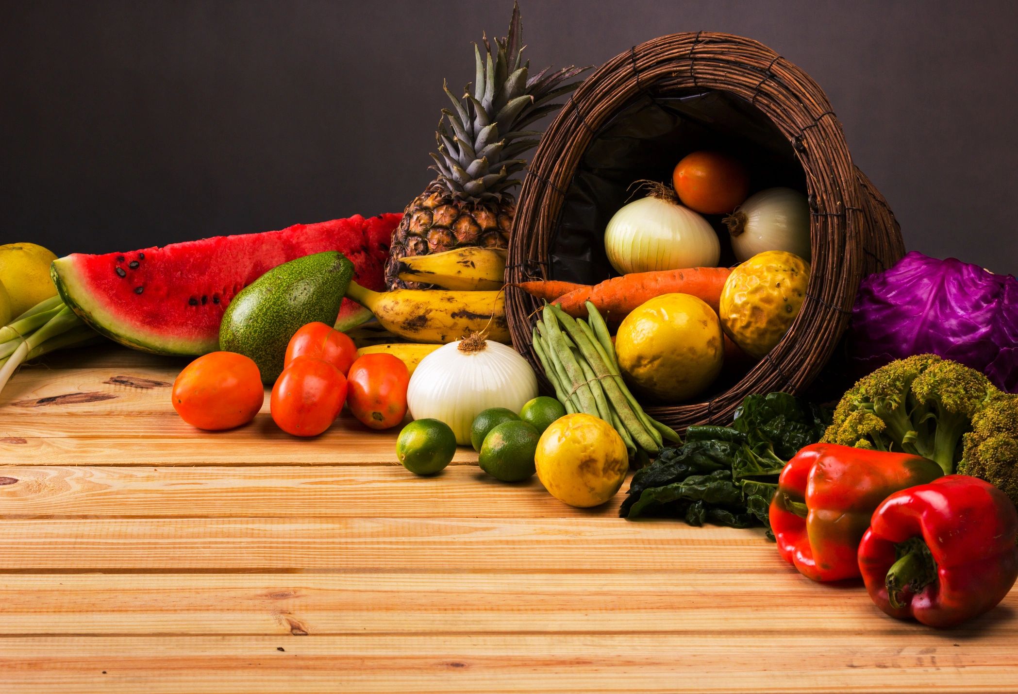 Basket and table full of colorful fruits and vegetables